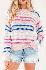 A woman wearing a pink knit sweater with horizontal stripes of blue, white, and pink, paired with light-wash denim shorts.