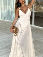 Woman in a white dress holding a gold clutch in an indoor setting.