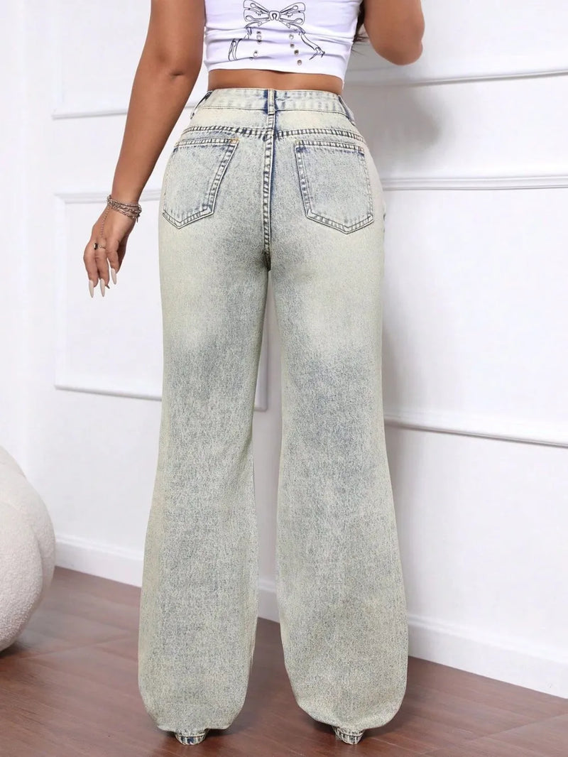 Person wearing light blue wide-leg jeans against a white wall.