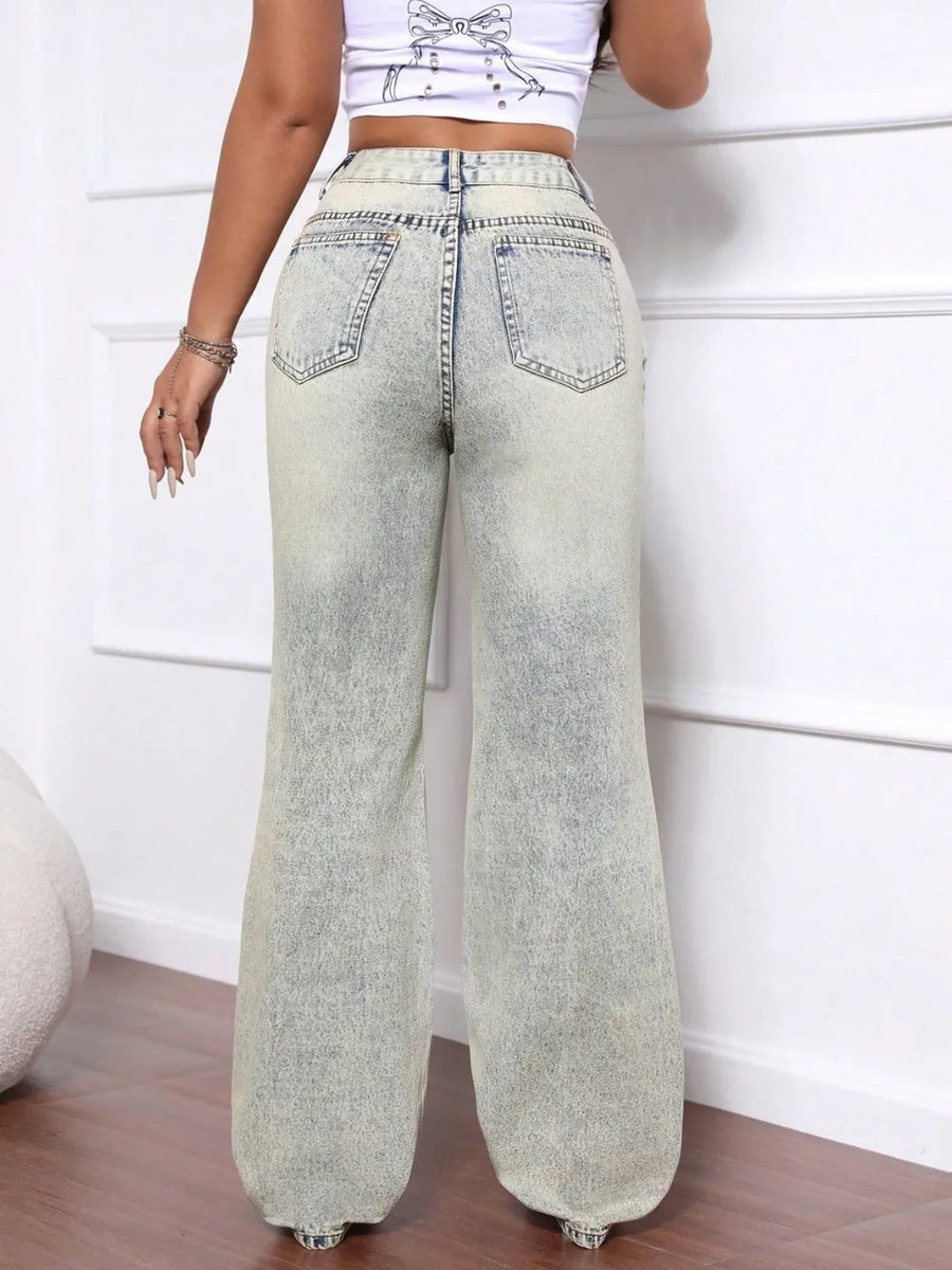 Person wearing light blue wide-leg jeans against a white wall.