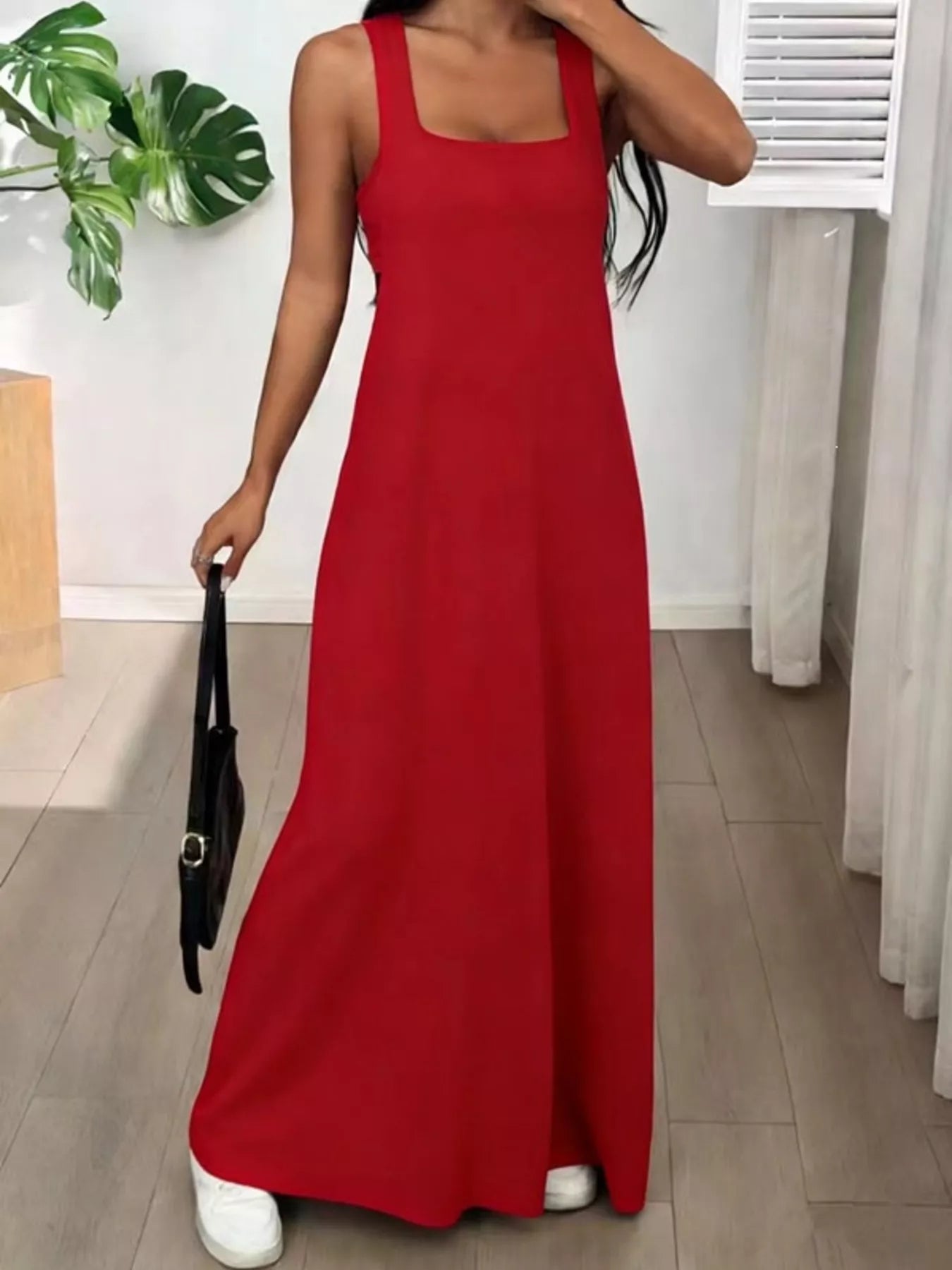 Person wearing a red dress holding a black handbag indoors.