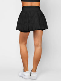 Black tennis skirt worn by a person on a white background