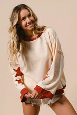 Woman wearing a cream sweater with red accents and white shorts on a beige background