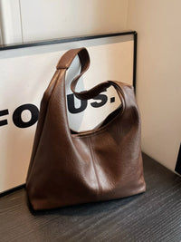 Brown leather handbag on a wooden surface with a blurred background