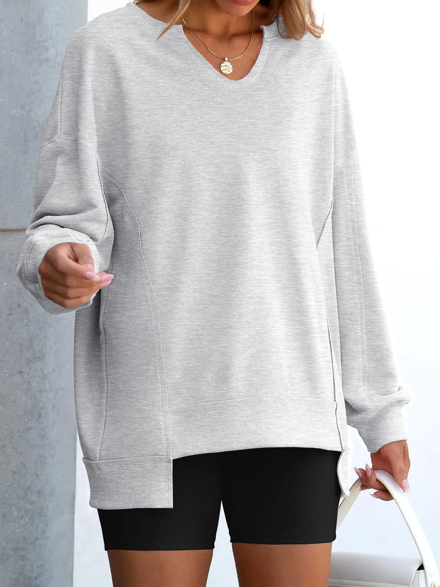 Person wearing a gray oversized sweatshirt and black shorts against a light background