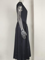 Black dress with a metallic arm on a mannequin against a plain background