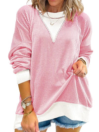 Pink textured sweater over a white shirt with denim shorts on a white background