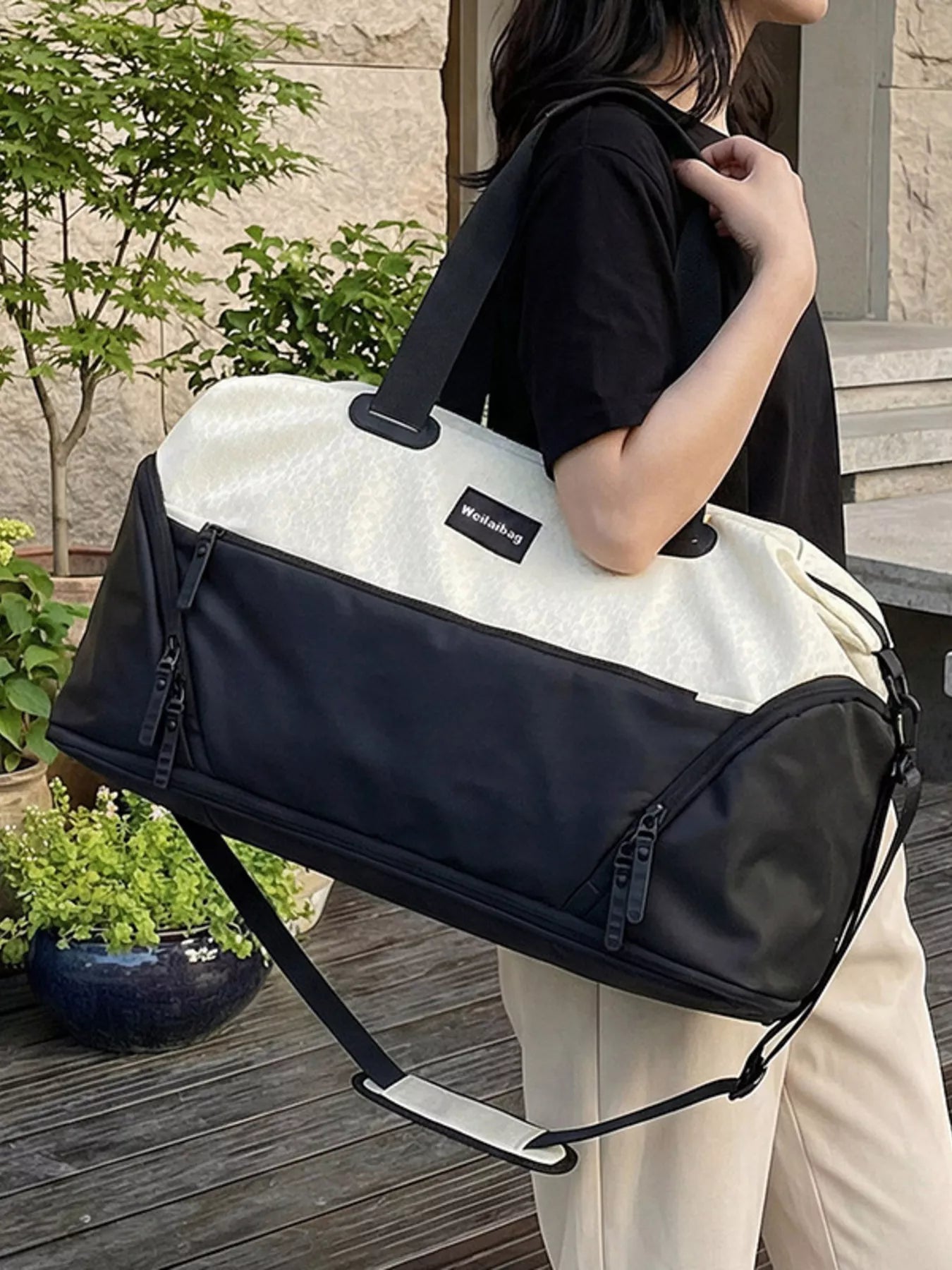 Person holding a black and white duffel bag with a visible brand logo.