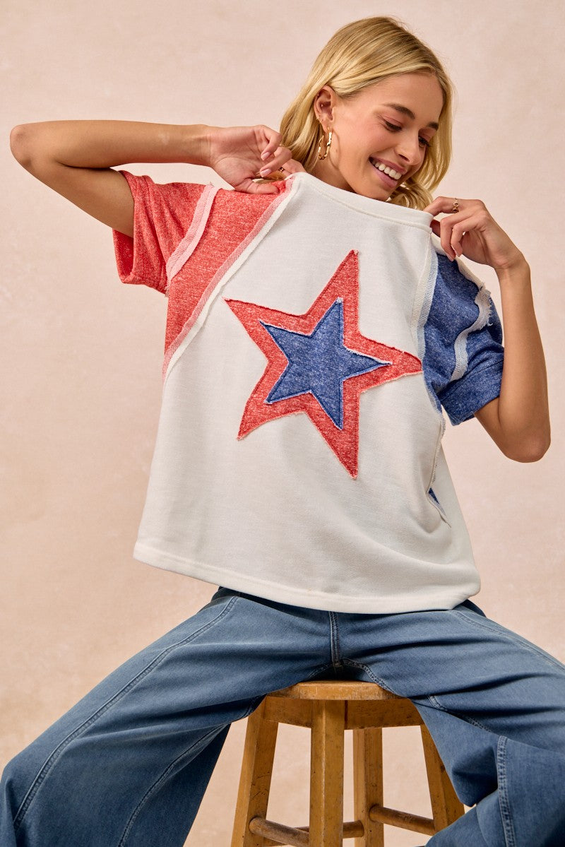 Woman holding a white t-shirt with a red and blue star design against a beige background