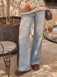 Person wearing light blue jeans and a patterned sweater in an outdoor setting.