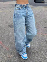 Person wearing light blue jeans and blue sneakers on a concrete surface