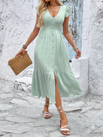 Woman wearing a light green dress with a textured surface, standing against a stone wall.