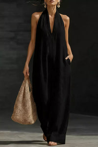 Woman wearing a black sleeveless dress holding a woven bag against a dark background