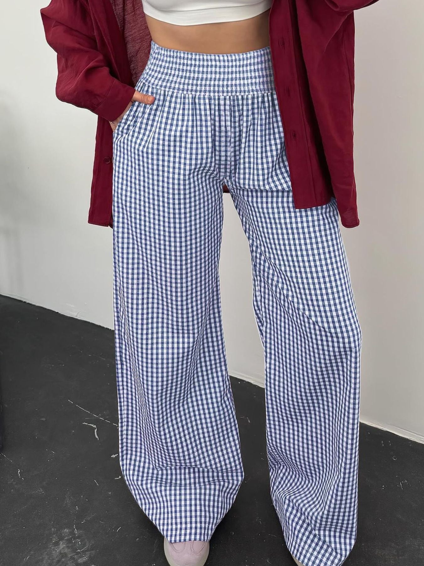 Person wearing blue and white checkered pants with a red jacket over shoulders.