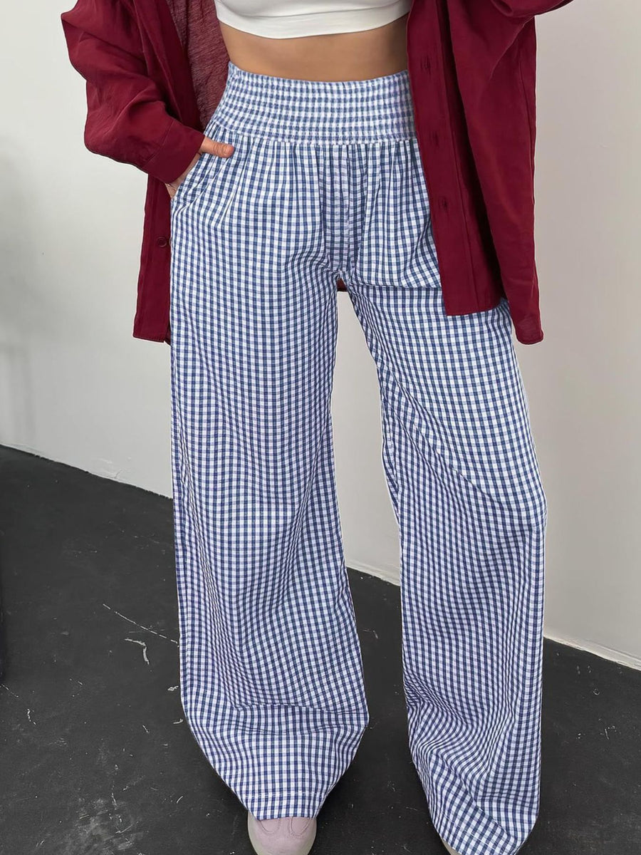 Person wearing blue and white checkered pants with a red jacket over shoulders.