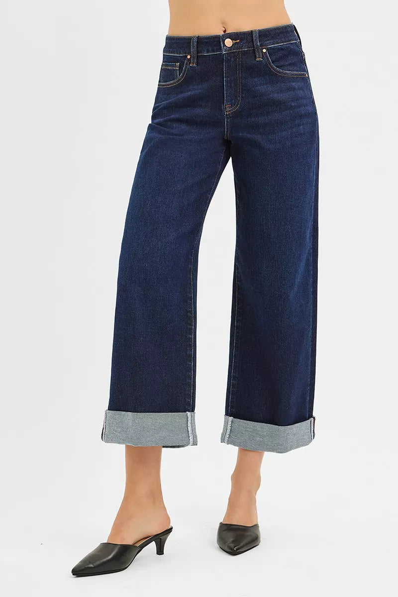 Dark blue wide-leg jeans worn by a person on a white background