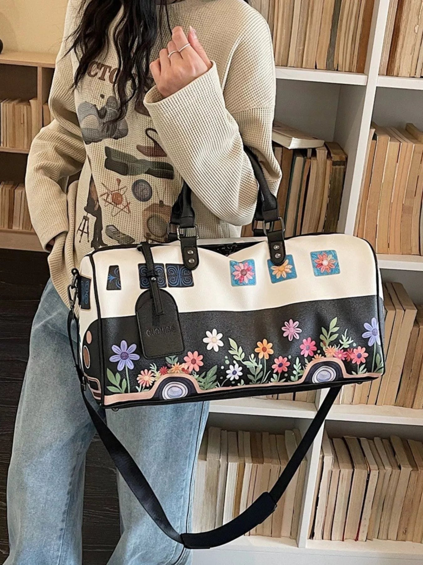 Person holding a floral-patterned handbag with a bookshelf in the background
