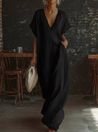 Person wearing a black dress in a dimly lit room with wooden chairs.