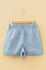 Blue striped shorts on a wooden hanger against a beige background