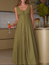 Woman in a green dress holding a glass of wine in a kitchen setting