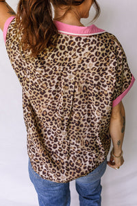 Person wearing a leopard print top with pink trim and blue jeans on a white background