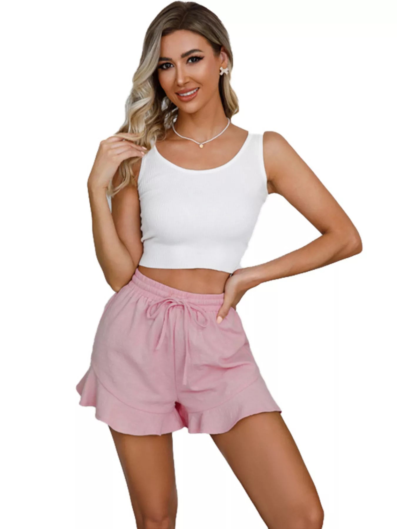Woman wearing a white tank top and pink shorts on a white background