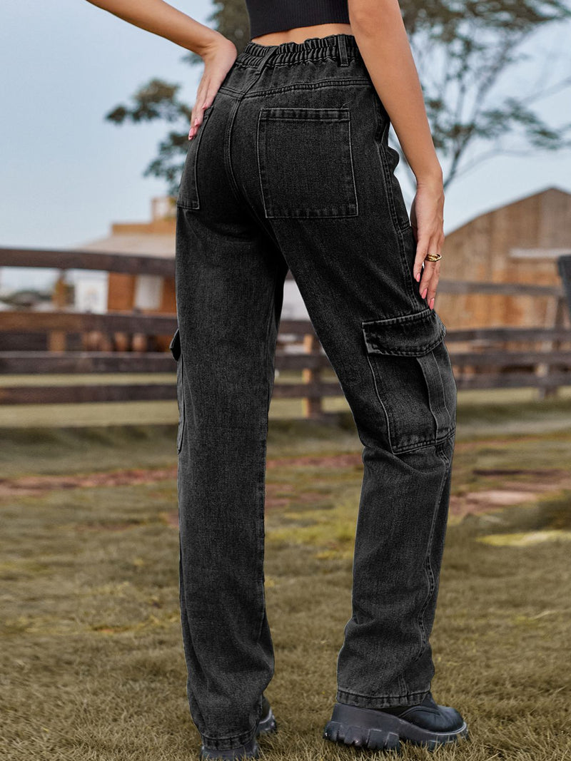 Person wearing black cargo pants standing outdoors with a wooden fence and trees in the background