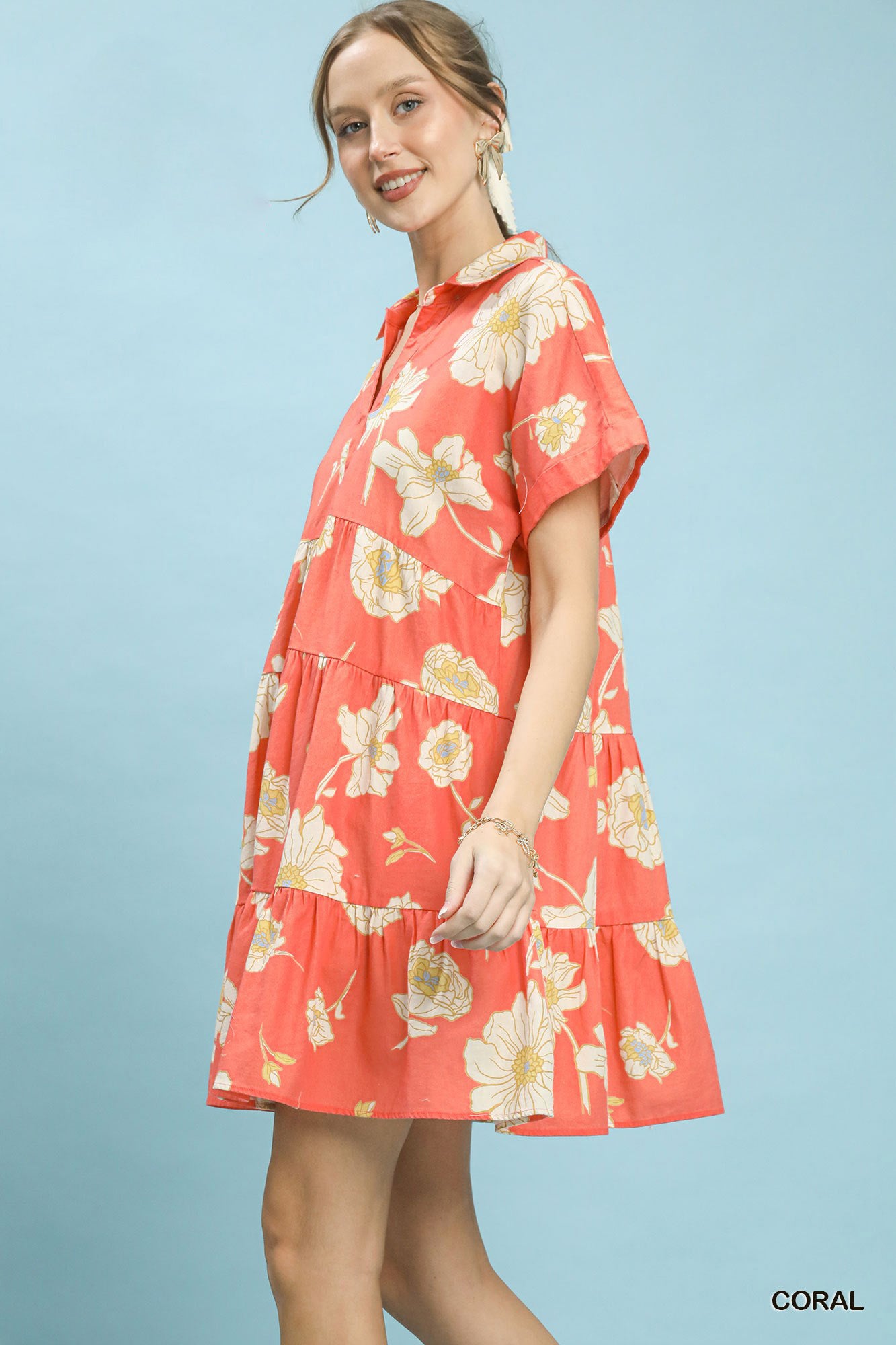 Woman wearing a coral floral dress against a light blue background