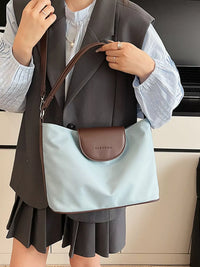 Person holding a light blue and brown handbag with 'Clarke' branding.