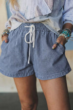 Person wearing blue striped shorts with a blurred background