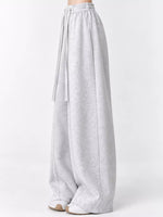 Light gray heathered wide-leg sweatpants with an elastic waistband and drawstring, shown on a model from the waist down against a plain white studio background.