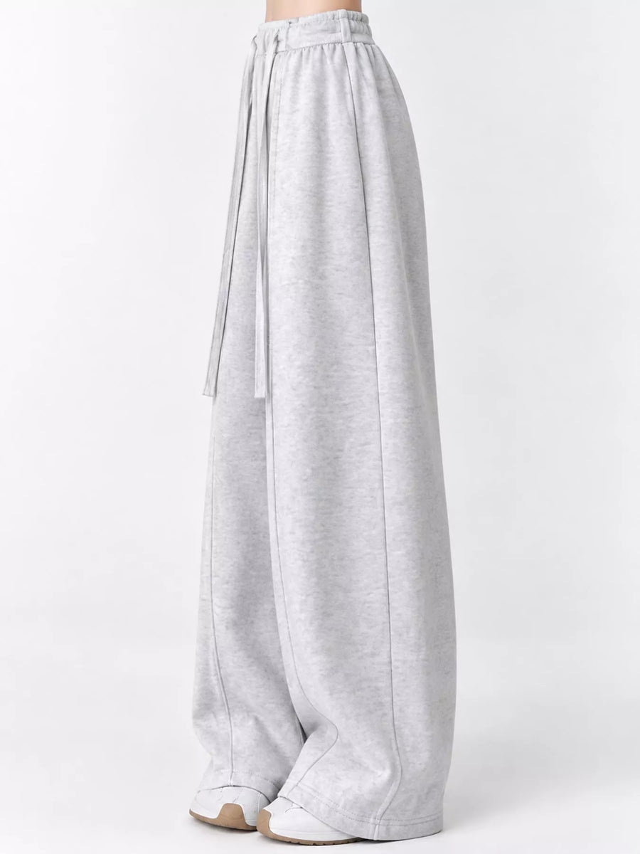 Light gray heathered wide-leg sweatpants with an elastic waistband and drawstring, shown on a model from the waist down against a plain white studio background.