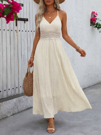 Woman wearing a white dress with floral details against a white wall.