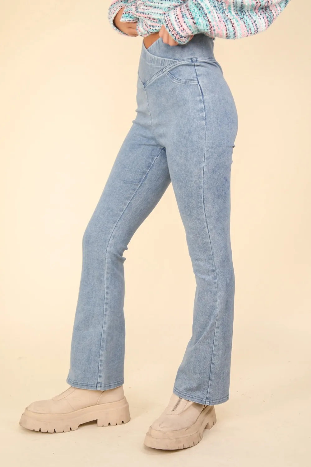 Light blue jeans worn by a person on a beige background