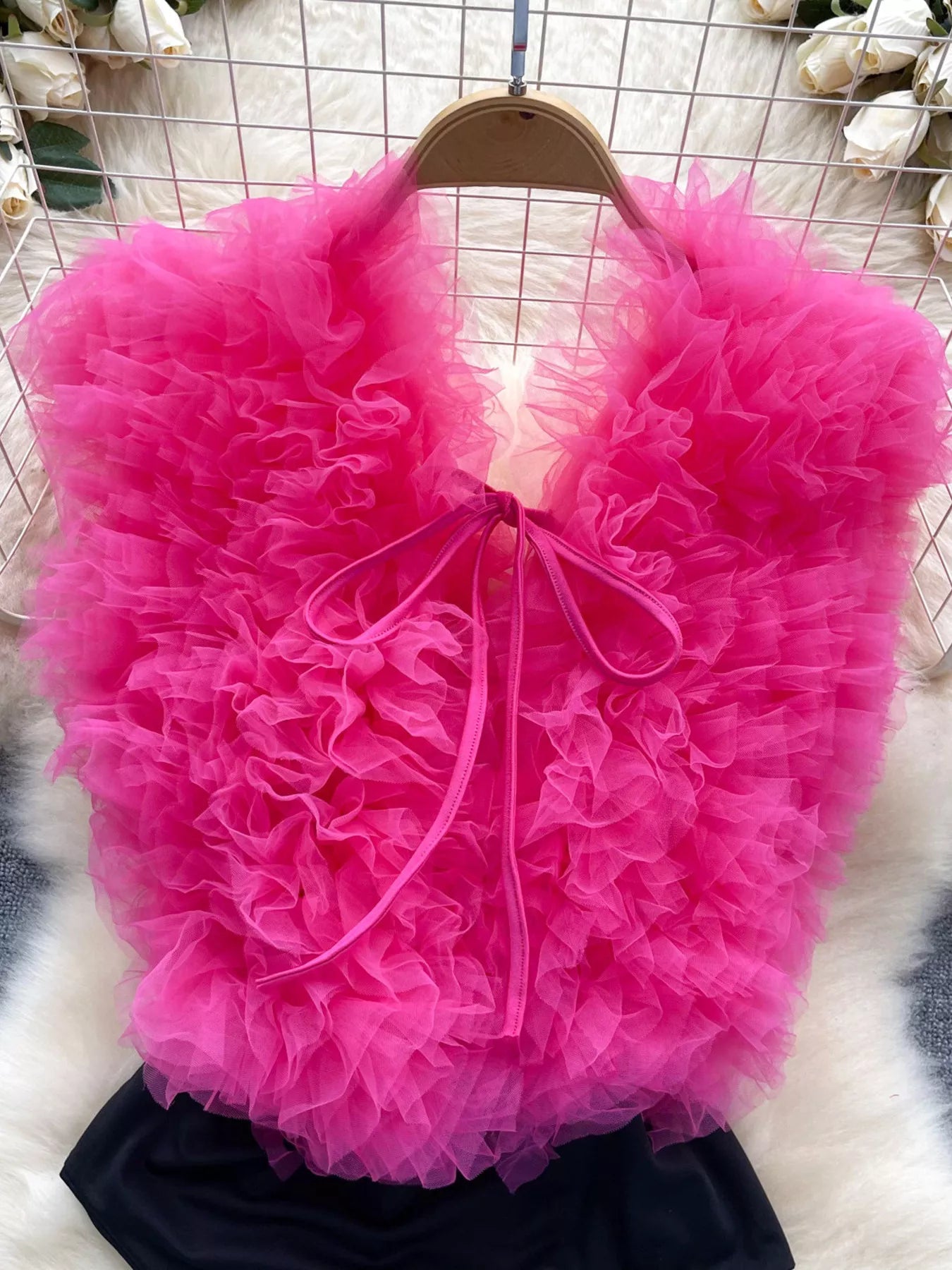 Pink ruffled bag on a hanger against a wire mesh background