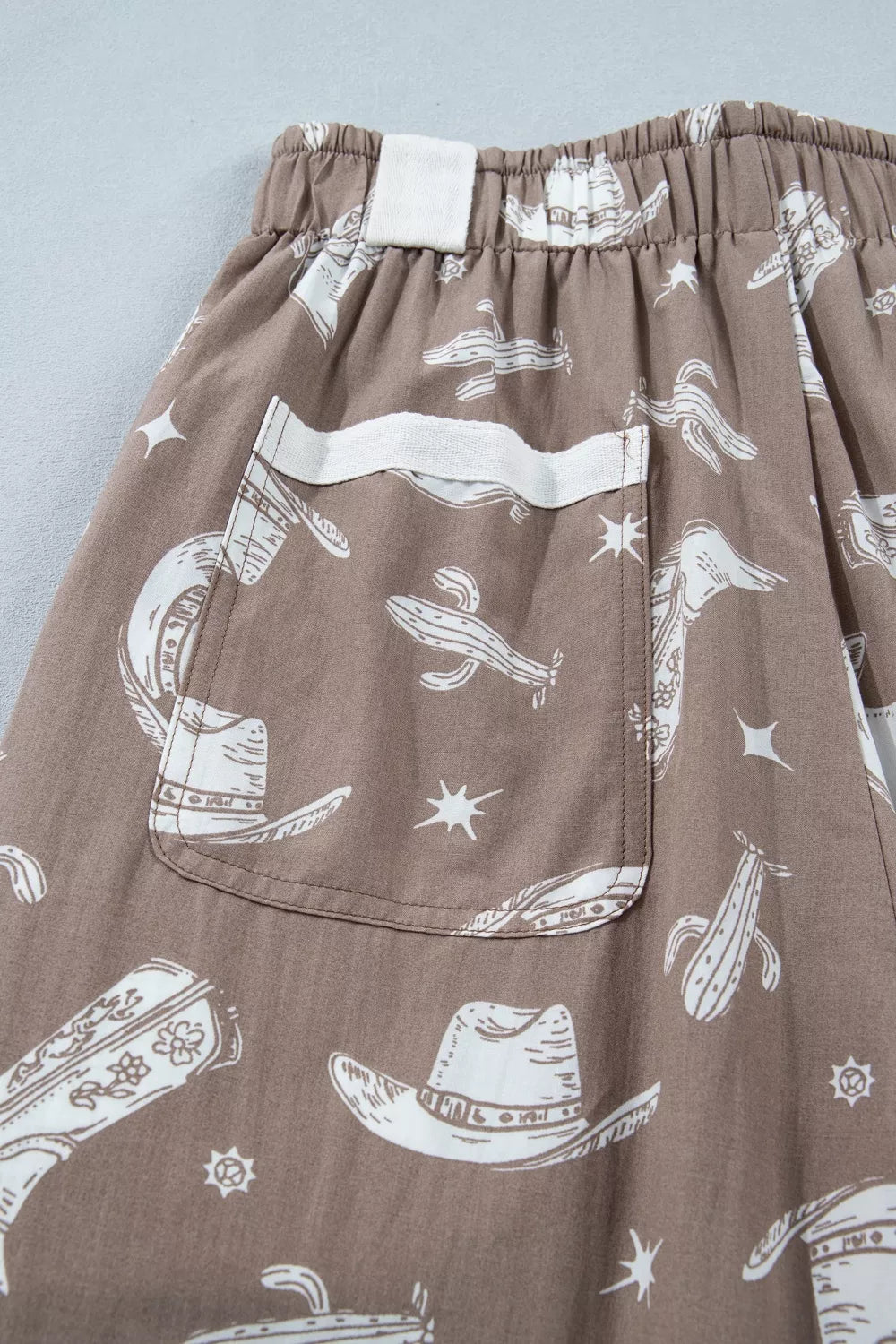 Brown shorts with white graphic designs on a light gray background
