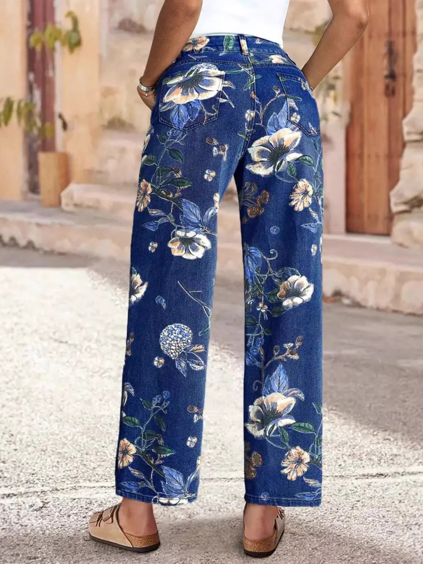 Blue floral pants worn by a person on a stone pavement.