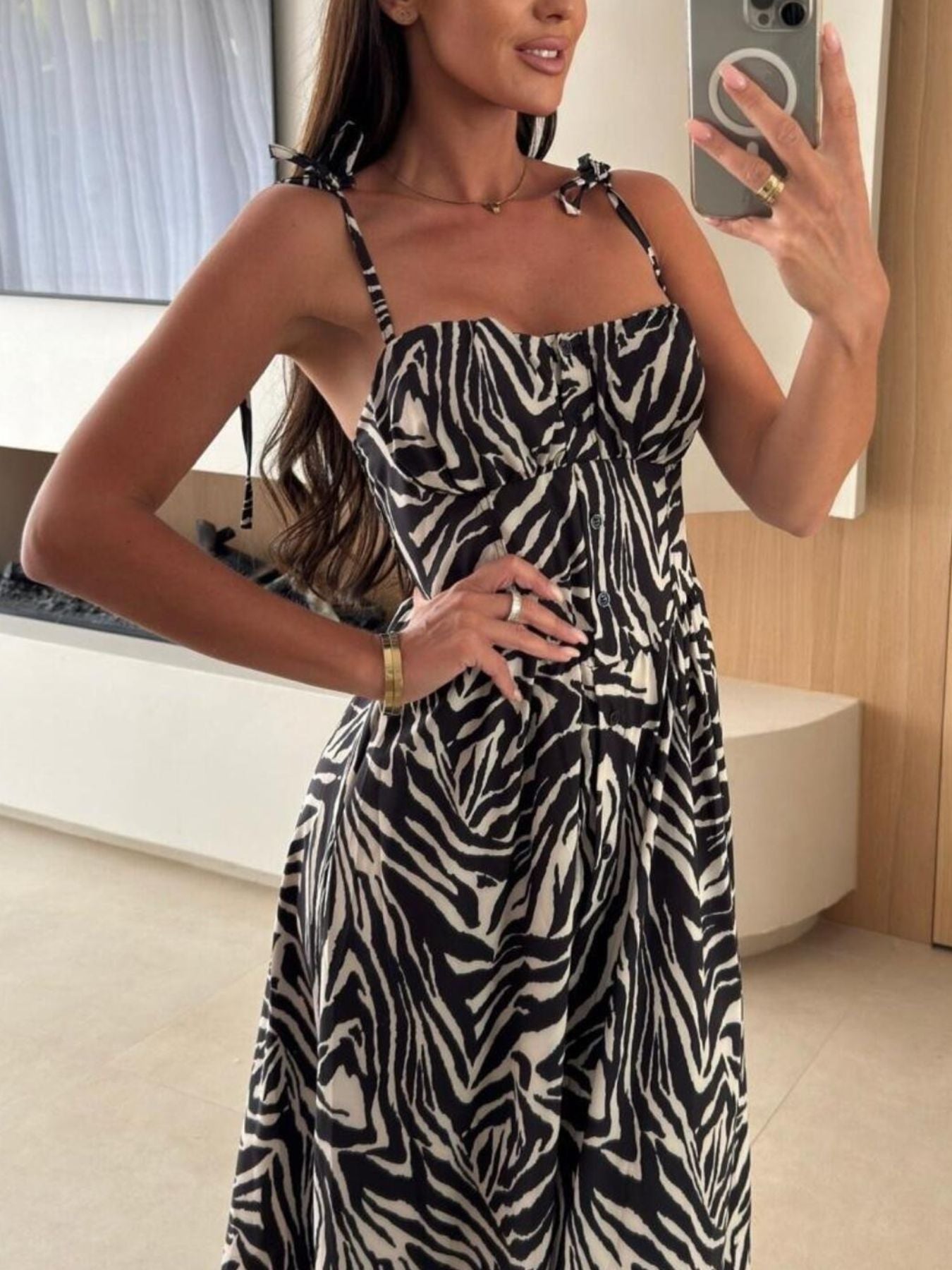 Woman taking a mirror selfie wearing a zebra print dress indoors.