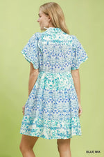 Woman wearing a blue and green patterned dress on a light green background