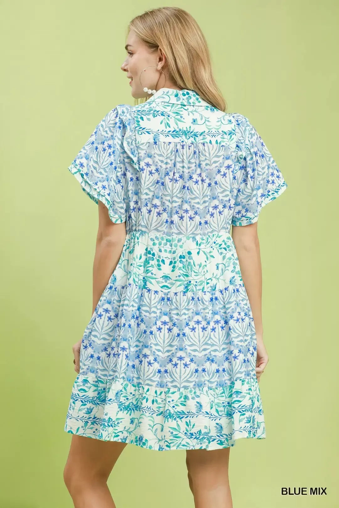 Woman wearing a blue and green patterned dress on a light green background