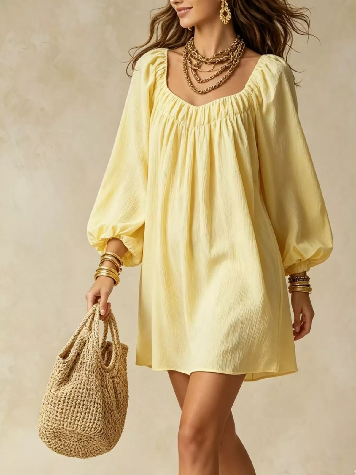 A woman wearing a pale yellow puff-sleeve mini dress with a square neckline, holding a woven straw tote bag against a textured beige background.