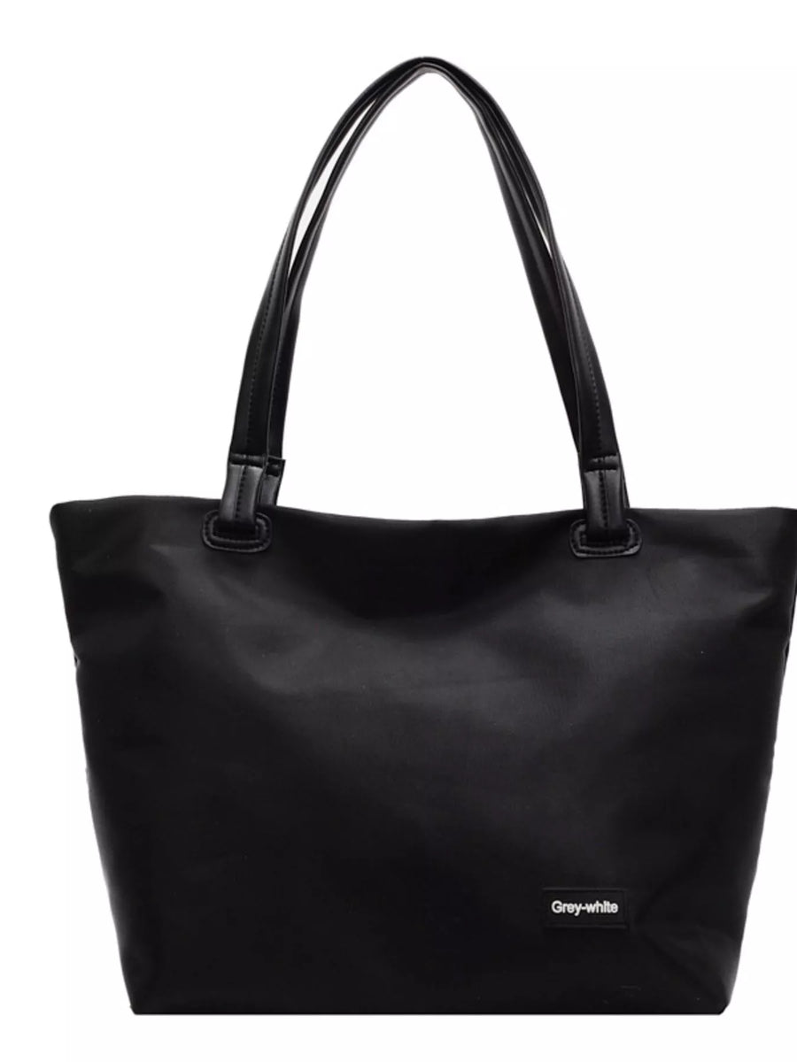 Black tote bag with a visible brand label on a white background