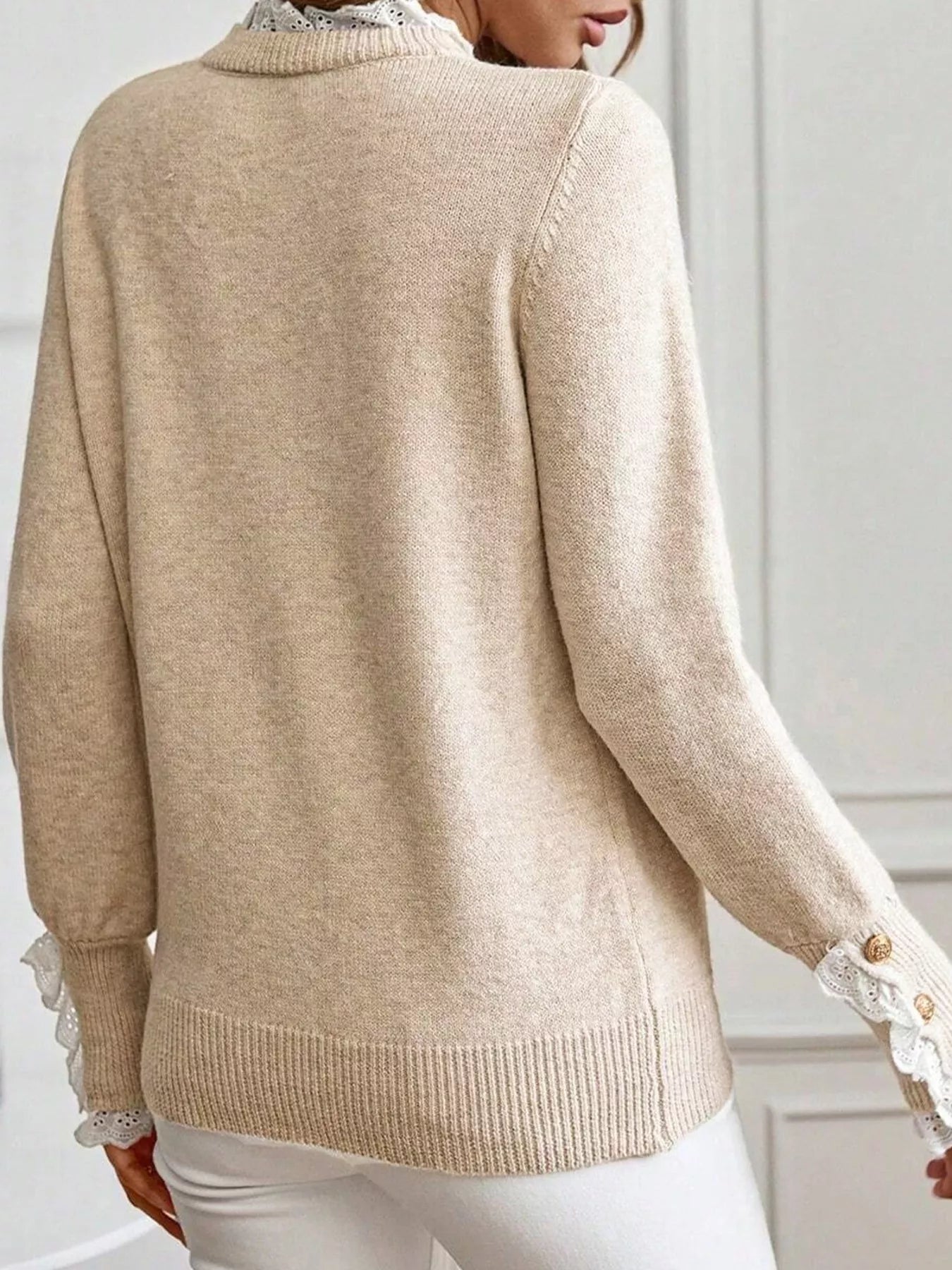 Beige sweater with lace details on cuffs and hem worn by a person.