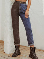 Person wearing a two-tone brown and blue jeans outfit with boots on a light wooden floor.