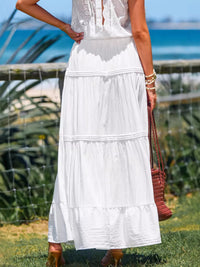Person wearing a white dress with a blurred background of greenery and water.