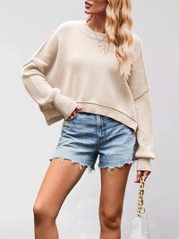 Woman wearing a beige sweater and denim shorts on a plain background