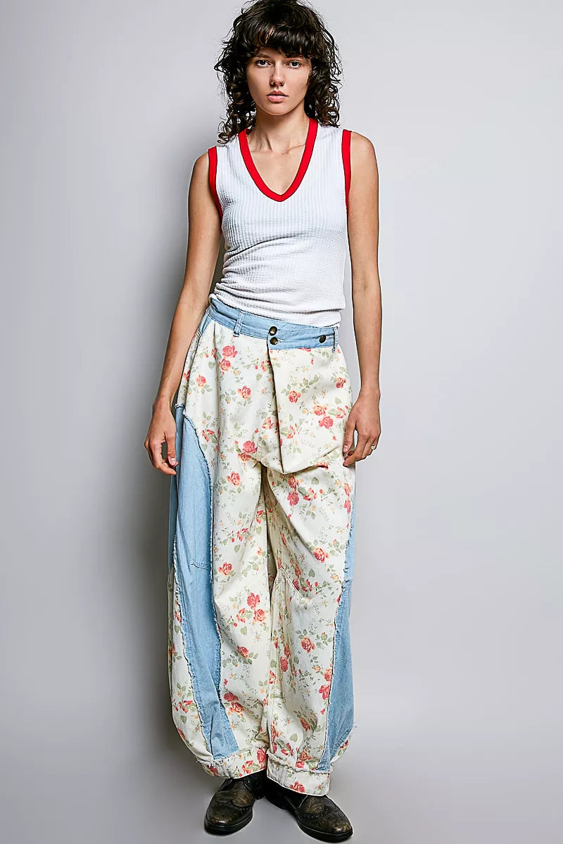 Woman wearing a sleeveless top and floral pants with a gray background