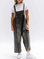 Person wearing gray distressed overalls on a white background