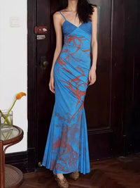 Woman wearing a blue evening gown with red patterns in a room.
