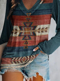 Person wearing a long-sleeve shirt with a geometric pattern and denim shorts on a plain background